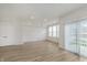 Sunlit living room with sliding doors, wood-look flooring, and interior doors to bedrooms at 7324 Shroyer Way, Noblesville, IN 46062
