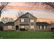 Charming two-story stone and wood home with a well-maintained lawn and colorful sunset sky at 9132 Log Run N Dr, Indianapolis, IN 46234