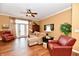 Comfortable living room with natural lighting, ceiling fan, hardwood floors, and red sitting chairs at 9640 Clover Leaf Ln, Fishers, IN 46038