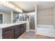 Bathroom featuring a double vanity, large mirrors, tiled floor, separate tiled shower, and soaking tub at 12777 Rotterdam Rd, Fishers, IN 46037