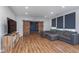 Spacious living room featuring wood floors, a large sectional sofa, and custom barn door access to the shelving area at 12777 Rotterdam Rd, Fishers, IN 46037