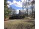 View of an older home with a covered porch, surrounded by mature trees and a gravel driveway at 1621 Ruth Dr, Indianapolis, IN 46240