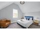 Cozy bedroom with vaulted ceiling, comfortable bed, and chair near the window at 1724 Prospect St, Indianapolis, IN 46203