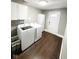 A well-lit laundry room featuring a washer, dryer, storage cabinet and wood floor at 1724 Prospect St, Indianapolis, IN 46203