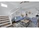 A modern living room features blue furniture, a staircase, and natural light at 1724 Prospect St, Indianapolis, IN 46203