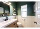 Charming powder room with green walls, white wainscoting, stylish fixtures, and decorative shelving at 19149 Gillcrest Dr, Noblesville, IN 46062
