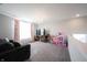 Spacious living area featuring a gray sofa, chandelier, and large windows with pink curtains at 19149 Gillcrest Dr, Noblesville, IN 46062
