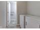 Bright laundry area with white washer and dryer, adjacent to a powder room with matching gray walls and flooring at 3039 Armory Dr, Indianapolis, IN 46208
