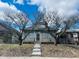 Modest single-story home featuring a stone facade, metal security door, and mature trees in front of the property at 428 N Alton Ave, Indianapolis, IN 46222