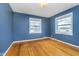 Bedroom featuring hardwood floors, two windows, and blue painted walls providing natural light at 4905 N Dearborn St, Indianapolis, IN 46205