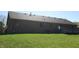 View of backyard with brick ranch home, wood deck, and grassy yard with treeline at 540 Louise Dr, Indianapolis, IN 46217