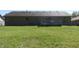 View of backyard with brick ranch home, wood deck, grassy yard and treeline at 540 Louise Dr, Indianapolis, IN 46217