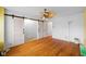 Bedroom with hardwood floors, ceiling fan, and closet with sliding barn doors at 5630 N Rockingham Ln, McCordsville, IN 46055