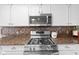 Close up of the stainless steel oven range and backsplash with granite countertops at 5630 N Rockingham Ln, McCordsville, IN 46055