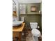 Bathroom features modern sink, toilet, wood countertop, rustic decor, and wood-look flooring at 6688 Bellsville Pike, Columbus, IN 47201