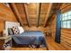 Warm bedroom with wood walls, vaulted ceiling with exposed beams, and a bed with blue linens at 7116 Grandview Rd, Columbus, IN 47201