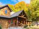 Beautiful log cabin with a welcoming porch, decorated for the season, and surrounded by vibrant fall foliage at 7116 Grandview Rd, Columbus, IN 47201