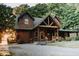 Stunning log cabin exterior featuring a covered porch, rocking chairs, and a well-maintained gravel driveway at 7116 Grandview Rd, Columbus, IN 47201