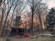 Outdoor view of a barn home with red Adirondack chairs around a fire pit in a wooded area at 7116 Grandview Rd, Columbus, IN 47201