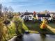 Aerial view of a backyard featuring a deck, lush green lawn, lake access, and mature trees at 7370 Chestnut Hills Blvd, Indianapolis, IN 46278
