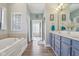 Bathroom featuring a soaking tub, glass block window, and blue vanity at 7370 Chestnut Hills Blvd, Indianapolis, IN 46278