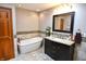 Bathroom featuring standalone tub, dark vanity, granite countertop, and stylish fixtures at 8513 Shelbyville Rd, Indianapolis, IN 46259