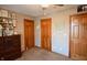 Neutral bedroom featuring three wood doors, carpeted floors, and a full dresser at 8513 Shelbyville Rd, Indianapolis, IN 46259
