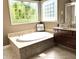Bathroom featuring a soaking tub with tiled surround, large windows, and elegant fixtures at 9615 N County Road 150 E Rd, Pittsboro, IN 46167