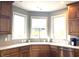 An open kitchen with plentiful counter space, wood cabinets, and sink beneath a bay window at 9615 N County Road 150 E Rd, Pittsboro, IN 46167
