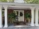 Charming home entrance with brick facade, white columns, wreath, and hanging ferns at 1020 W Riverview Dr, Anderson, IN 46011