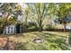 Large, grassy backyard with a fire pit, shed, and mature trees provides a serene outdoor space at 12601 Slippery Rock Rd, Indianapolis, IN 46236