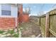 View of the backyard featuring partial brick wall, weathered wooden fence, and overgrown ground at 3125 Anniston Dr, Indianapolis, IN 46227