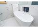 Close up of a sleek, white soaking tub set against marble walls with stylish blue tile accents at 3406 E 20Th St, Indianapolis, IN 46218