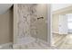 Walk-in shower with marble tile and a tiled inset next to an open doorway at 360 S Spencer Ave, Indianapolis, IN 46219