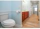 Bright bathroom with a toilet and vanity with wood cabinets, access to the hallway at 3677 Cedar Cove Ct, New Palestine, IN 46163