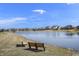 Relaxing view of a tranquil pond with benches, surrounded by lush greenery and charming homes at 3677 Cedar Cove Ct, New Palestine, IN 46163