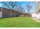 A grassy backyard with mature trees, brick wall, and wood fence at 3732 Wellington Ave, Indianapolis, IN 46226