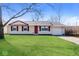 Charming single-story home with a well-manicured lawn, attached garage, and inviting red door at 3732 Wellington Ave, Indianapolis, IN 46226