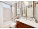 Well-lit bathroom with marble countertop, wood cabinets, bathtub and shower combo, and decorative wallpaper at 4215 Heyward Pl, Indianapolis, IN 46250