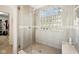 Close up of the glass-enclosed shower with glass-block window and neutral-toned tile at 4215 Heyward Pl, Indianapolis, IN 46250
