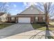 Traditional brick home featuring a two-car garage, manicured lawn, sidewalk, and beautiful architectural details at 5115 Baltustrol Dr, Avon, IN 46123