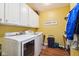 Functional laundry room with washer, dryer, storage cabinets, and laminate flooring at 5115 Baltustrol Dr, Avon, IN 46123
