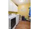 Well-lit laundry room with white cabinets, wooden floor, and modern washer and dryer at 5115 Baltustrol Dr, Avon, IN 46123