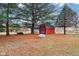 Red storage shed in a backyard setting surrounded by large mature trees at 520 Denny Dr, Mooresville, IN 46158