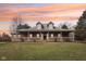 Charming brick home with a long front porch, dormer windows, and a well-manicured lawn under a colorful sunset sky at 520 Denny Dr, Mooresville, IN 46158