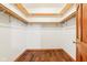Bright walk-in closet with wood flooring, open shelving, and wood trim at 520 Denny Dr, Mooresville, IN 46158