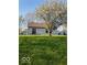 Backyard featuring green lawn, mature tree, and access to the home through the sliding glass door at 5851 Brobeck Ln, Indianapolis, IN 46254