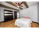 Bright bedroom with exposed beams, wood floors, and a classic dresser offers a blend of rustic charm and modern comfort at 7143 W 50 S, Morgantown, IN 46160