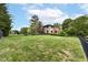 Expansive lawn sloping toward a backyard pond, enclosed with black fencing, and mature trees at 7645 Ballinshire N, Indianapolis, IN 46254
