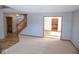 Open-concept living room with plush carpeting, staircase view, and an open doorway to the kitchen at 777 West St, Whiteland, IN 46184